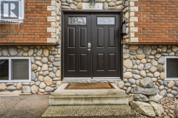 Close-up of the front entrance with dark brown double doors and stained glass. - 1206 39b Avenue, Vernon