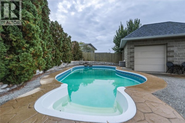 Backyard with a kidney-shaped swimming pool and a detached garage. - 1206 39b Avenue, Vernon