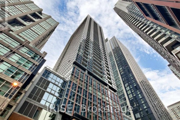 Looking up at tall modern glass and steel apartment buildings under a cloudy sky. - 1207 - 88 Blue Jays Way, Toronto