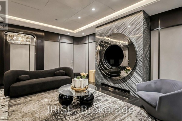 A modern living room with a dark sofa, circular coffee table, and marble fireplace feature. - 1207 - 88 Blue Jays Way, Toronto