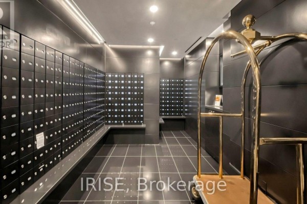 A hallway with rows of black mailboxes and a brass luggage cart. - 1207 - 88 Blue Jays Way, Toronto