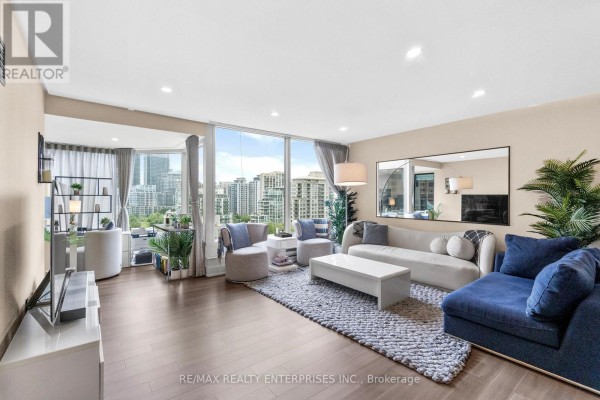 Living room with large windows, a blue sectional sofa, white sofa, and a coffee table. - 1208 - 1 Palace Pier Court, Toronto