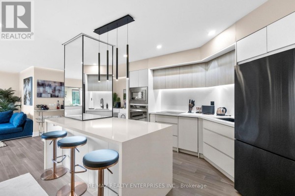 Modern kitchen with a large island, white countertops, and stainless steel appliances. - 1208 - 1 Palace Pier Court, Toronto