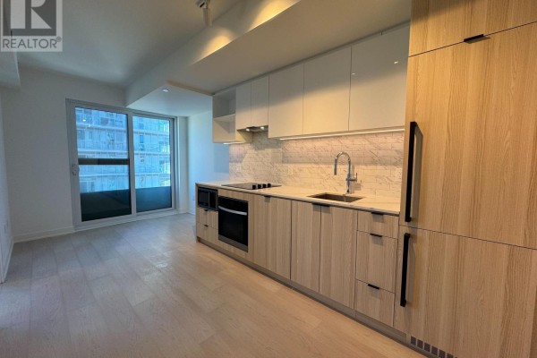 Modern kitchen with light wood cabinetry, white backsplash, and stainless steel appliances. - 1208 - 252 Church Street, Toronto