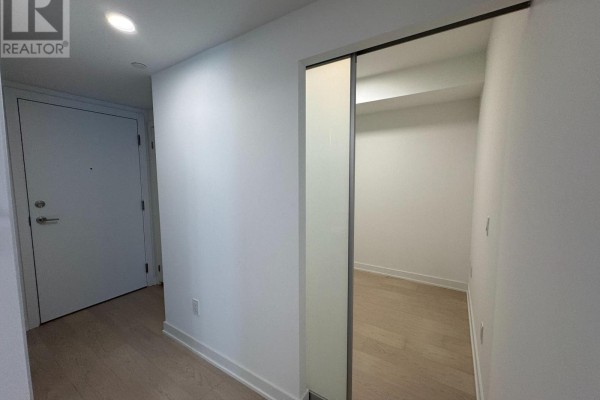 Hallway leading to apartment entrance door and an open closet or storage area. - 1208 - 252 Church Street, Toronto