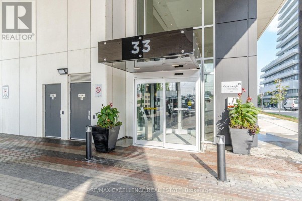 Glass entrance doors with number 33 above and potted plants on the side. - 1208 - 33 Shore Breeze Drive, Toronto