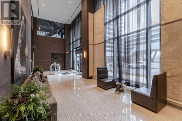 Luxurious condo lobby with seating, tall windows, and modern decor. - 1208 - 33 Shore Breeze Drive, Toronto