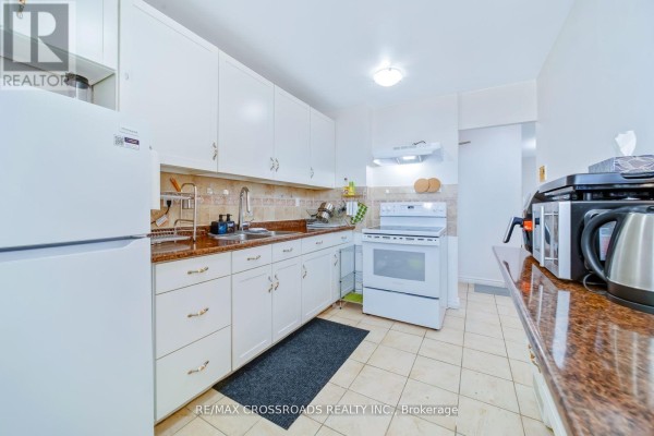 Kitchen with white cabinets, granite counters, oven, and sink - 1208 - 340 Dixon Road Toronto