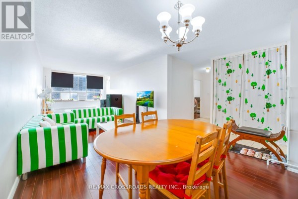Living room with striped sofa, dining table, TV, and tree curtains - 1208 - 340 Dixon Road Toronto