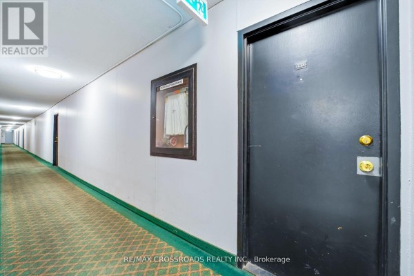 Hallway with unit 1208 door, fire hose cabinet, and green carpet - 1208 - 340 Dixon Road Toronto