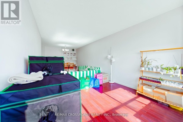 Living room with striped sofa, plants on shelves, storage units, and hardwood floors - 1208 - 340 Dixon Road Toronto