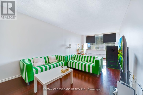 Green and white striped sofa, TV, and coffee table in living room - 1208 - 340 Dixon Road Toronto