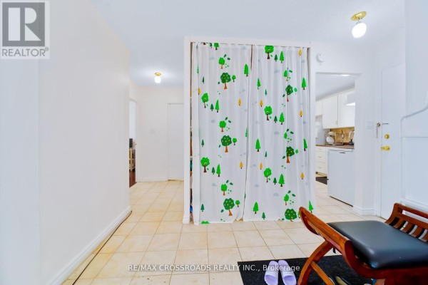 Hallway with decorative tree curtain, tiled floor, bench, and kitchen view - 1208 - 340 Dixon Road Toronto