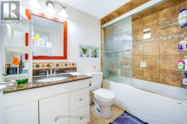 Bathroom with granite vanity, glass shower door, and bathtub - 1208 - 340 Dixon Road Toronto