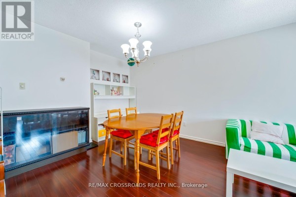 Dining and living area with wooden table, chairs, striped sofa, fireplace, and hardwood floors - 1208 - 340 Dixon Road Toronto