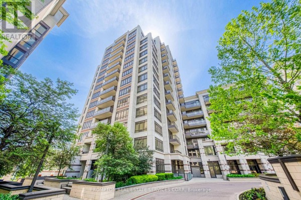 Exterior view of a tall condominium building with balconies and surrounding green trees. - 1208 - 38 Cedarland Drive, Markham