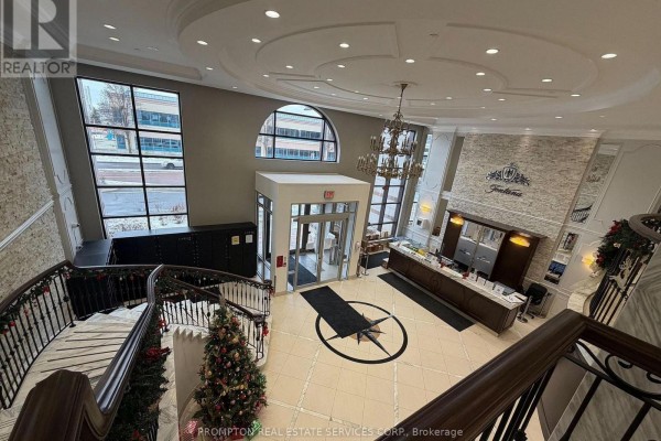 View of the building lobby from above, showing the reception desk, entrance, and a spiral staircase. - 1208 - 38 Cedarland Drive, Markham