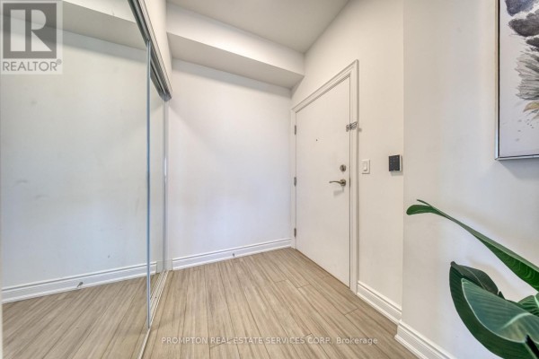 Apartment entryway with a large mirrored closet door, white walls, and light wood flooring. - 1208 - 38 Cedarland Drive, Markham