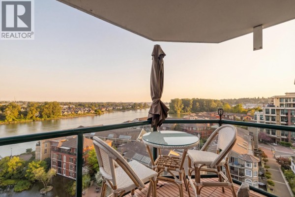 Balcony with a table, chairs, and umbrella overlooking the Fraser River and city. - 1208 10 Laguna Court, New Westminster