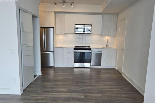 A contemporary kitchen with stainless steel appliances, white subway tile backsplash, and light wood cabinetry. - 1209 - 1350 Ellesmere Road, Toronto