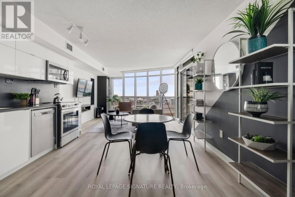 Kitchen and dining area with stainless steel appliances, a round dining table, and open shelving. - 1209 - 21 Iceboat Terrace, Toronto