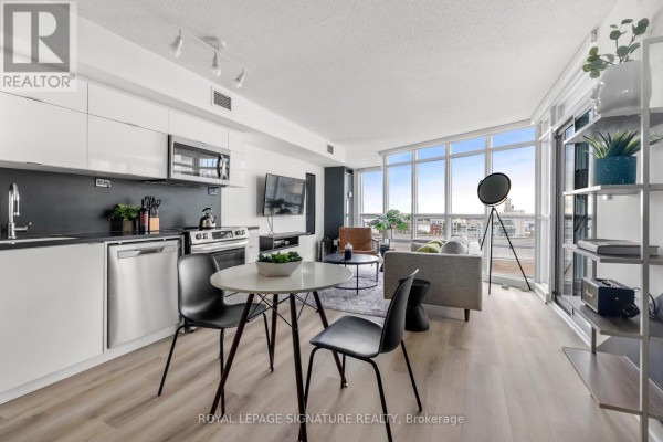 View of the open concept living space, including the kitchen and dining area, and city views. - 1209 - 21 Iceboat Terrace, Toronto