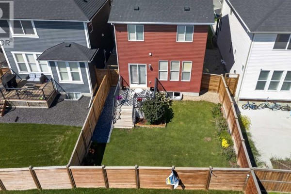 Front door with a wreath and hanging flower baskets on a porch. - 1209 Copperfield Boulevard Se, Calgary