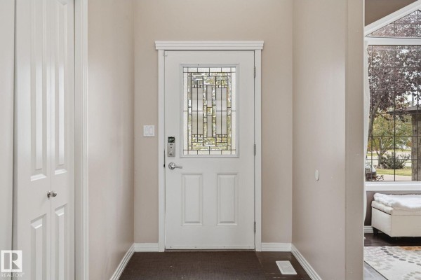 View of the foyer from the inside, showing the front door, a closet, and a large window. - 1209 Cunningham Dr Sw Sw, Edmonton