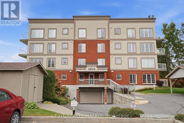 Exterior view of the apartment building showing the entrance, garages, and parking area. - 121 - 1404 Clement Street, Hawkesbury