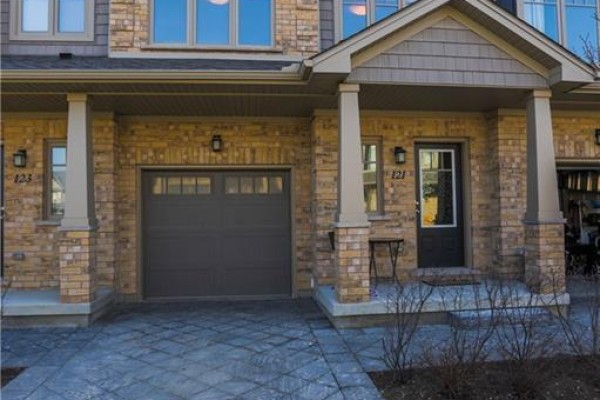 Close-up of townhouse entrance with garage and beige brick facade. - 121 - 1924 Cedarhollow Boulevard, London North