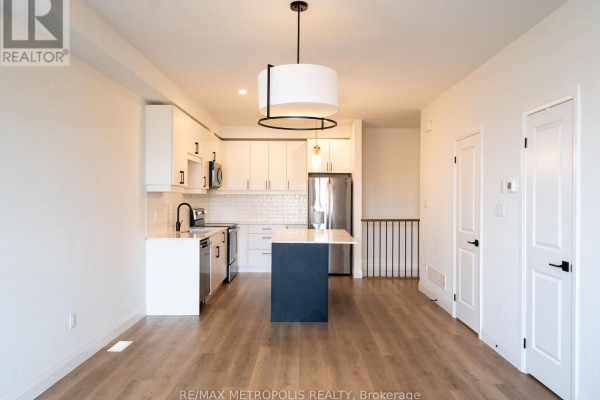 Open-concept living area with a modern kitchen, island, and wood floors. - 121 - 3900 Savoy Street, London South