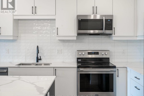 Close-up of stainless steel appliances, white subway tile backsplash, and dark faucet. - 121 - 3900 Savoy Street, London South