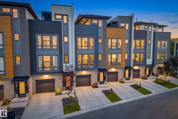 Aerial view of modern townhouse complex with grey, white, and wood siding, dusk. - #121 1304 Rutherford Rd Sw, Edmonton