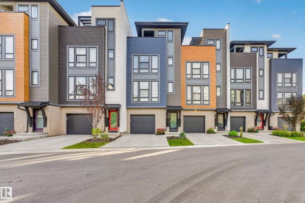 Front view of modern townhouse complex with grey, white, and orange siding, day. - #121 1304 Rutherford Rd Sw, Edmonton