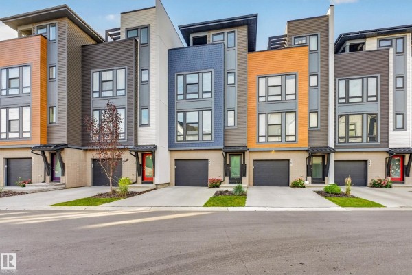 Front view of modern townhouse complex with grey, white, and orange siding, day. - #121 1304 Rutherford Rd Sw, Edmonton