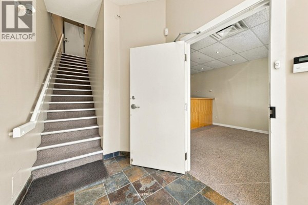 Interior hallway with slate tile floor, carpeted stairs, and an open door to a carpeted room. - 121 3989 Henning Drive, Burnaby