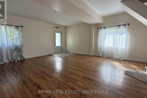 Living room with dark gray walls, wood-look laminate flooring, and an open view into the kitchen area. - 121 Boullee Street, London East