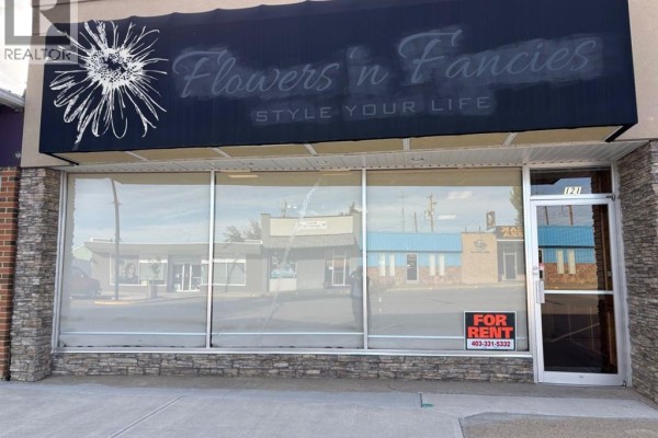 Exterior storefront with large display windows, a black awning, and "Flowers n Fancies" signage. - 121 Center Street W, Vulcan