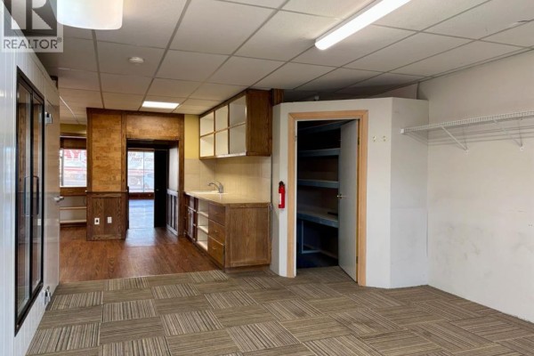 Interior commercial space with carpeted floor, kitchenette counter, sink, and a walk-in cooler. - 121 Center Street W, Vulcan