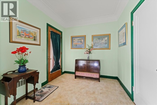 Interior entryway with pale green walls, a dark wood cabinet, and a wooden door with green trim. - 121 Division Street South, Kingsville