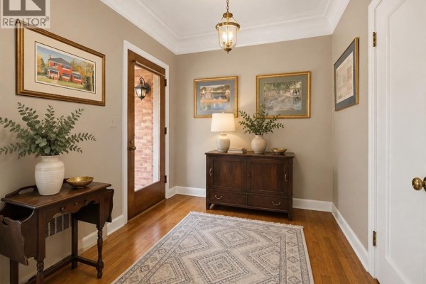 Living room with pale green walls, a piano, sofa, armchair, and archway to another room. - 121 Division Street South, Kingsville
