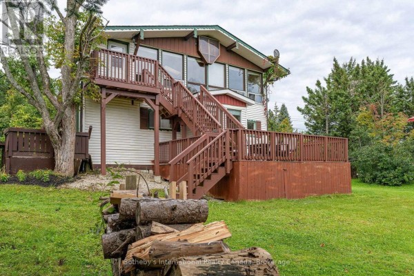 View of the house from the side with woodpile in foreground and wooden stairs. - 121 Hamlet Road, Blue Mountains