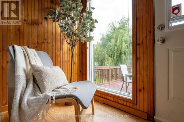 Chair and blanket by a large window overlooking the wooden deck. - 121 Hamlet Road, Blue Mountains