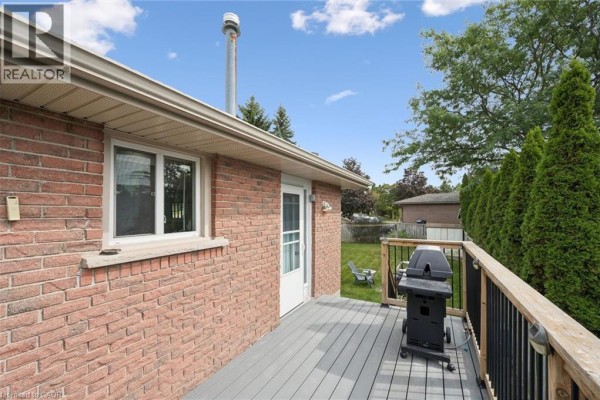 Deck with a barbecue and railing, overlooking the backyard and trees. - 121 Nathaniel Crescent, Kitchener