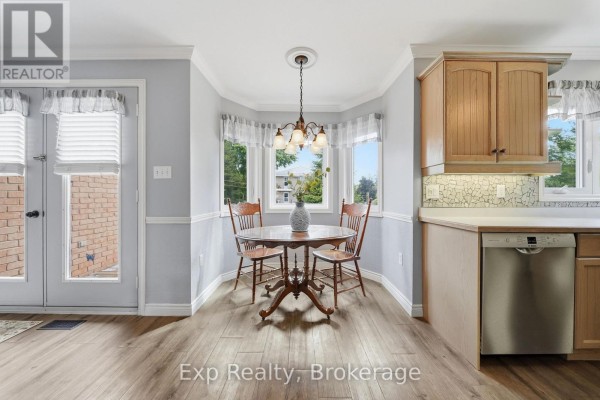Wooden dining table and chairs in a bay window next to kitchen cabinets and dishwasher - 121 Simcoe Street Greater Napanee