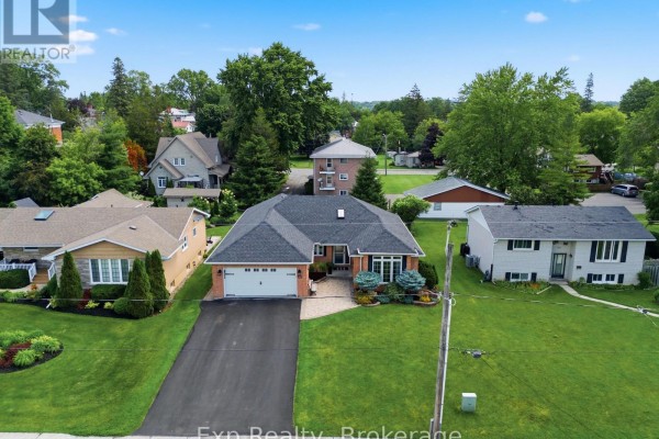Rear aerial view of the bungalow, showing a large backyard with decks and surrounding properties. - 121 Simcoe Street, Greater Napanee