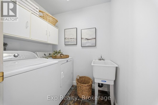 White washer and dryer, utility sink, and cabinets in laundry room - 121 Simcoe Street Greater Napanee