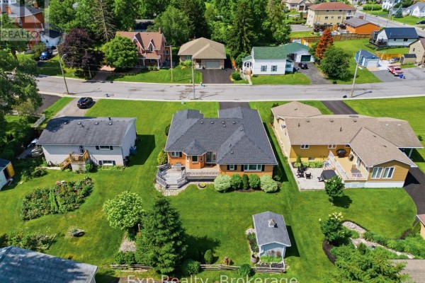 Front view of a red brick bungalow with a white garage door and manicured lawn. - 121 Simcoe Street, Greater Napanee