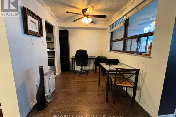 Dining area with a glass-top table and chairs, adjacent to a home office setup. - 1210 - 120 Saint Patrick Street N, Toronto