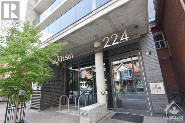 Entrance to the Gotham apartment building at 224 Lyon Street, featuring glass doors and metal bike racks. - 1210 - 224 Lyon Street, Ottawa